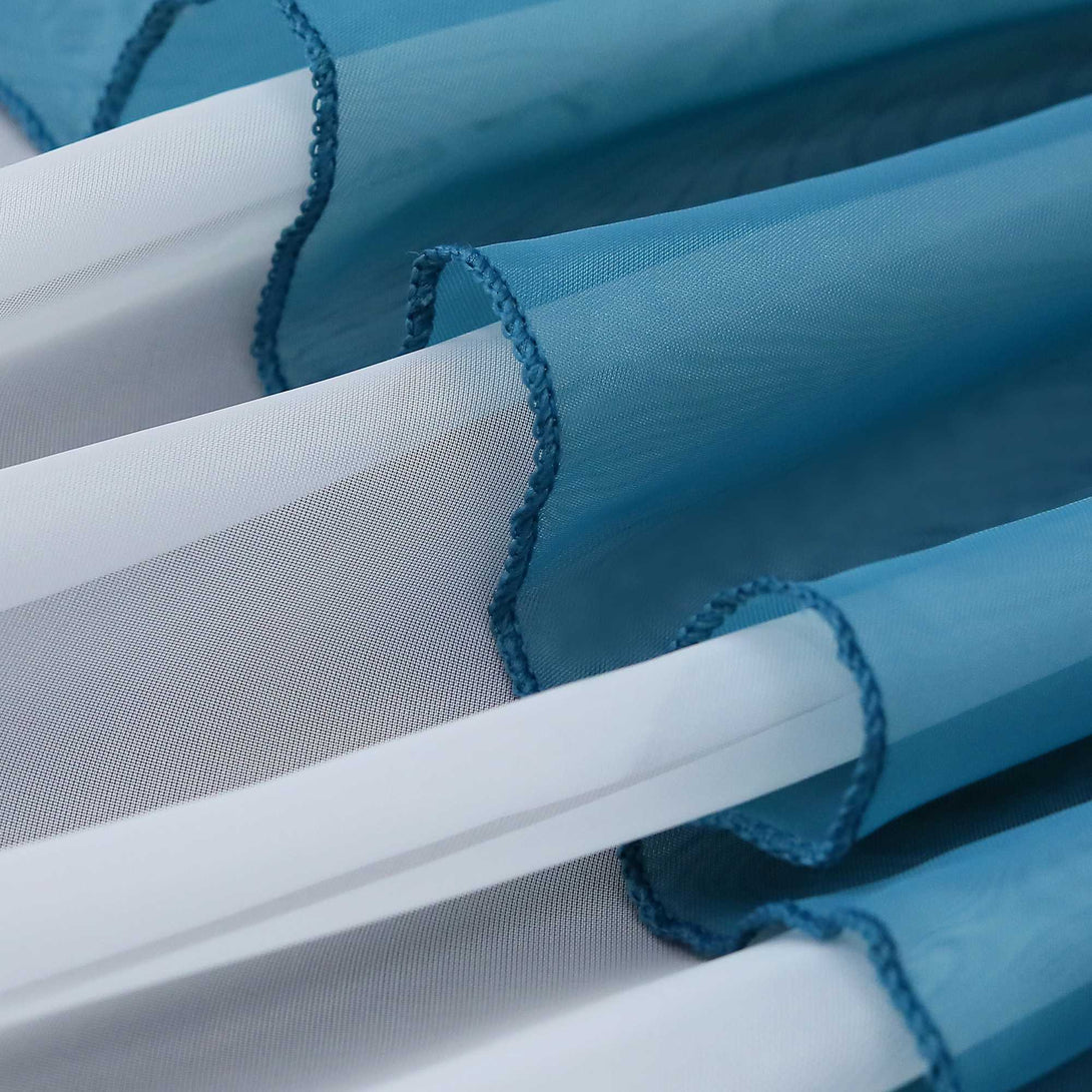 Nahaufnahme mehrerer Lagen eines blauen, halbtransparenten Gardinenstoffs. Die Falten erzeugen ein weiches, welliges Aussehen und reflektieren das Licht.