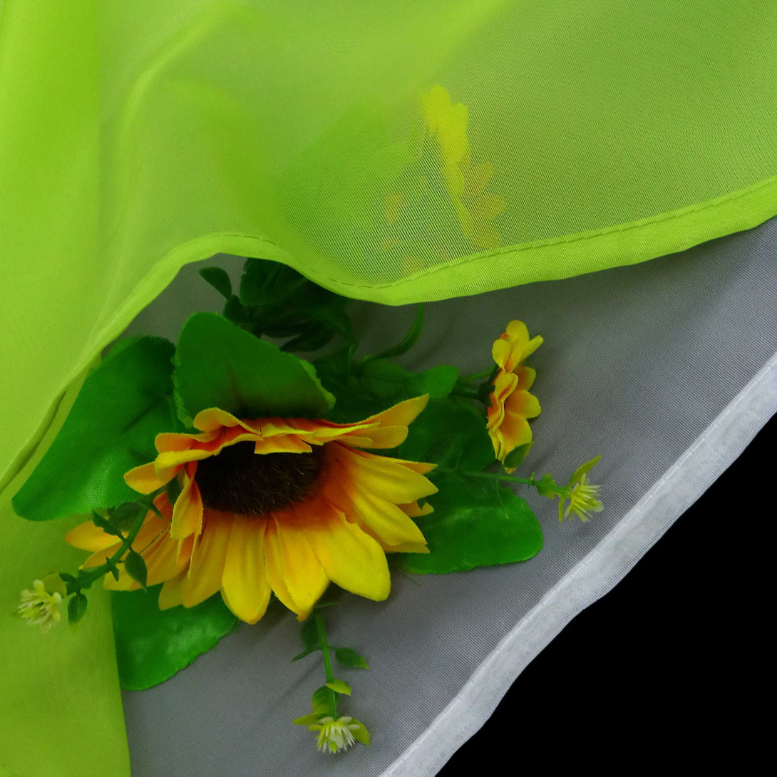 Detailaufnahme des grünen Stoffs mit halbdurchsichtiger Konstruktion. Darunter sind die Sonnenblumen zu sehen, und die oberen und unteren Vorhänge sind sauber gesäumt.