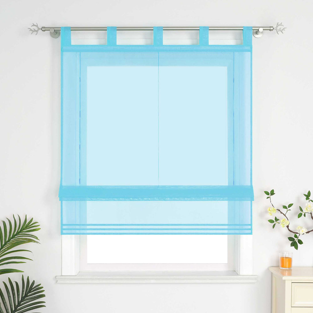 Im Wohnzimmer hängen blauefarbene Rollos. Daneben sind dekorative Grünpflanzen und Duftkerzen aufgestellt.