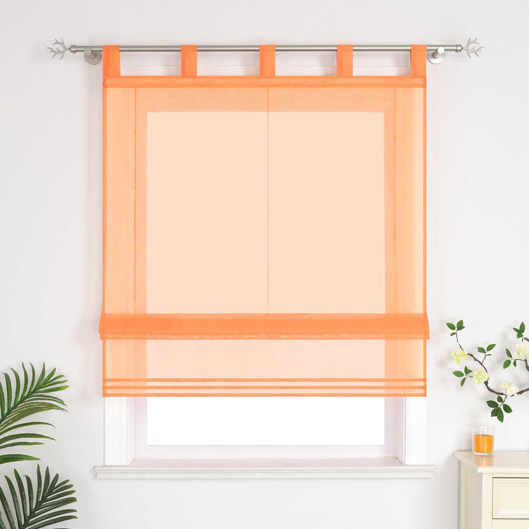 Im Wohnzimmer hängen orangefarbene Rollos. Daneben sind dekorative Grünpflanzen und Duftkerzen aufgestellt.