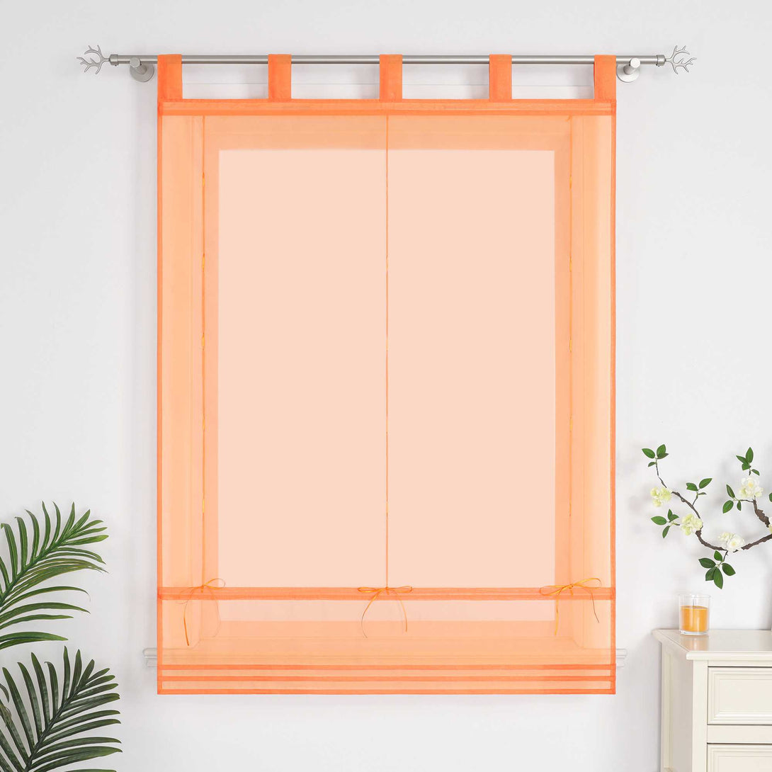 Im Wohnzimmer hängen orangefarbene Rollos. Neben ihnen stehen dekorative Grünpflanzen und Duftkerzen.