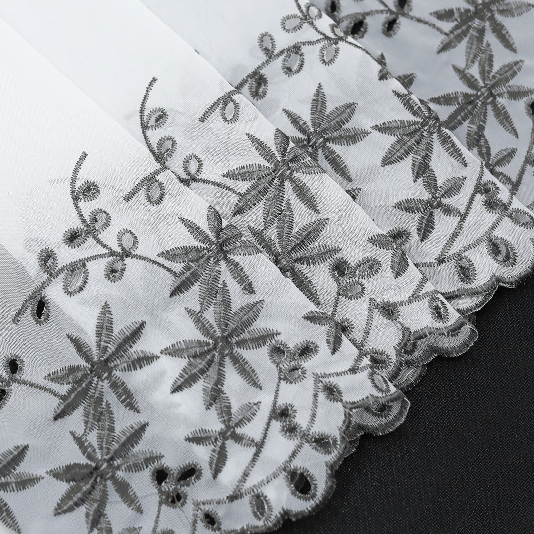 Ein lichtdurchlässiger Stoff mit aufwendig gesticktem floralen Muster in Schwarz. Der wellige Saum und die Stickereien aus Ahornblättern verleihen dem Vorhang eine elegante Optik.