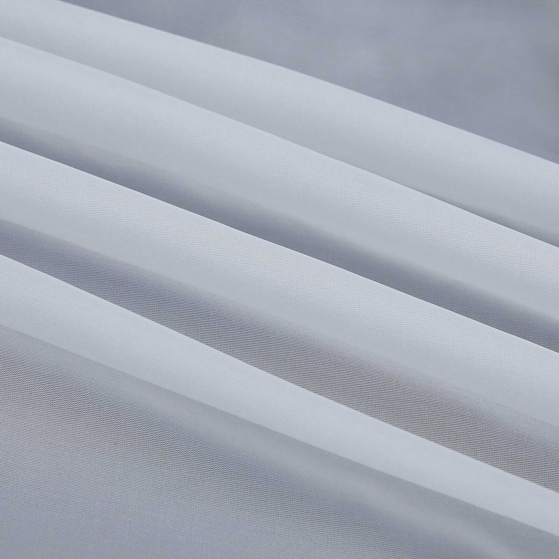 Detail eines grauen, halbtransparenten Gardinenstoffs mit deutlich sichtbarem Saum und sauber gefalteten Kanten. Die feine Struktur des Stoffes lässt das Licht sanft eindringen.