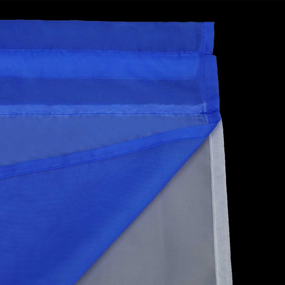 Detail eines marineblauen, halbtransparenten Gardinenstoffs mit sauber gefalteten Kanten. Die umgeschlagenen Kanten sind sauber und fein gepresst, und die oberste Lage des marineblauen Gardinenstoffs ist gegenüber dem darunter liegenden weißen Stoff halbdurchlässig.
