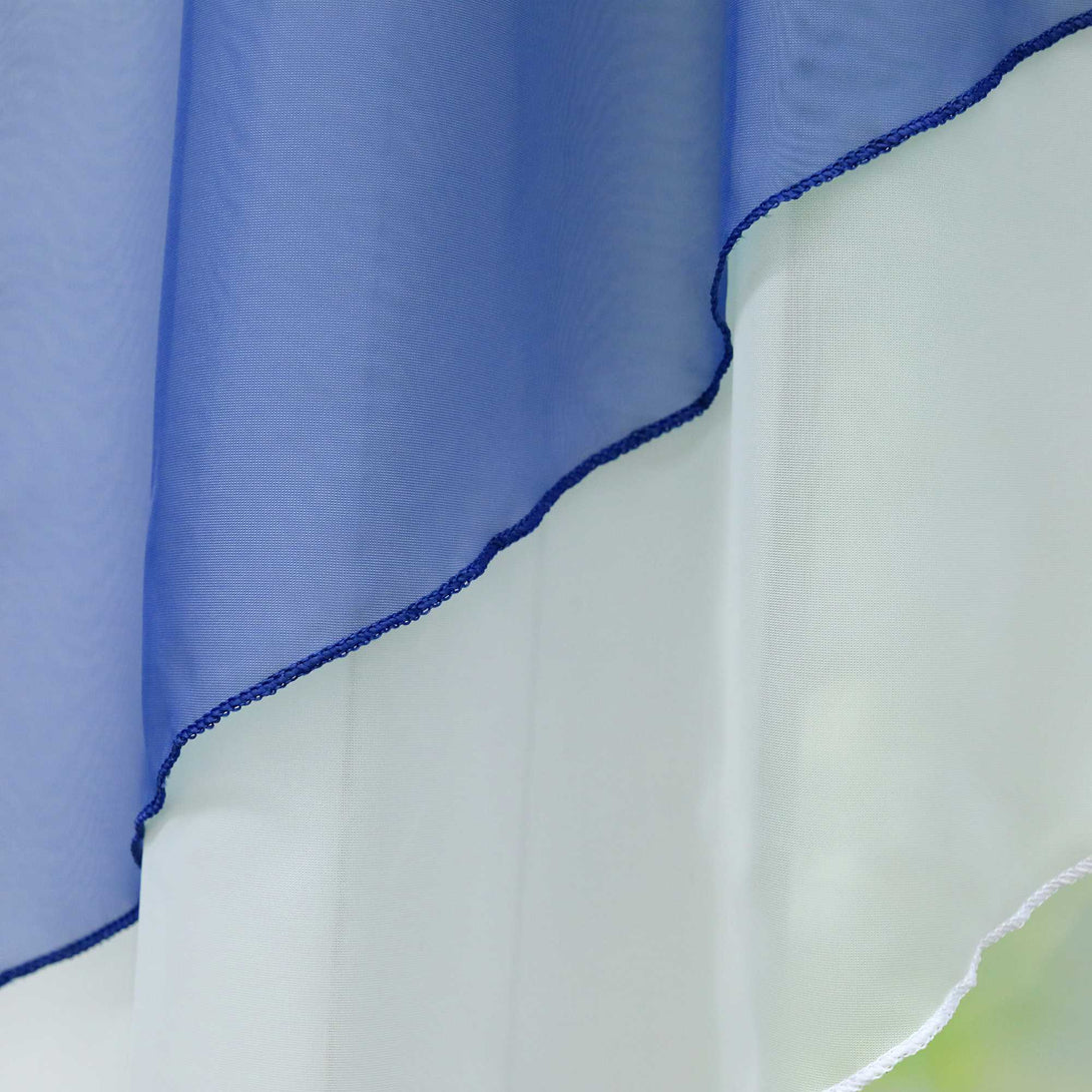 Nahaufnahme von halbtransparenten Gardinen in Marineblau mit gewellten Rändern, die sanft drapiert werden. Das Licht hebt die feine Struktur des Stoffes hervor, während der Hintergrund in einem sanften Grünton verschwimmt.