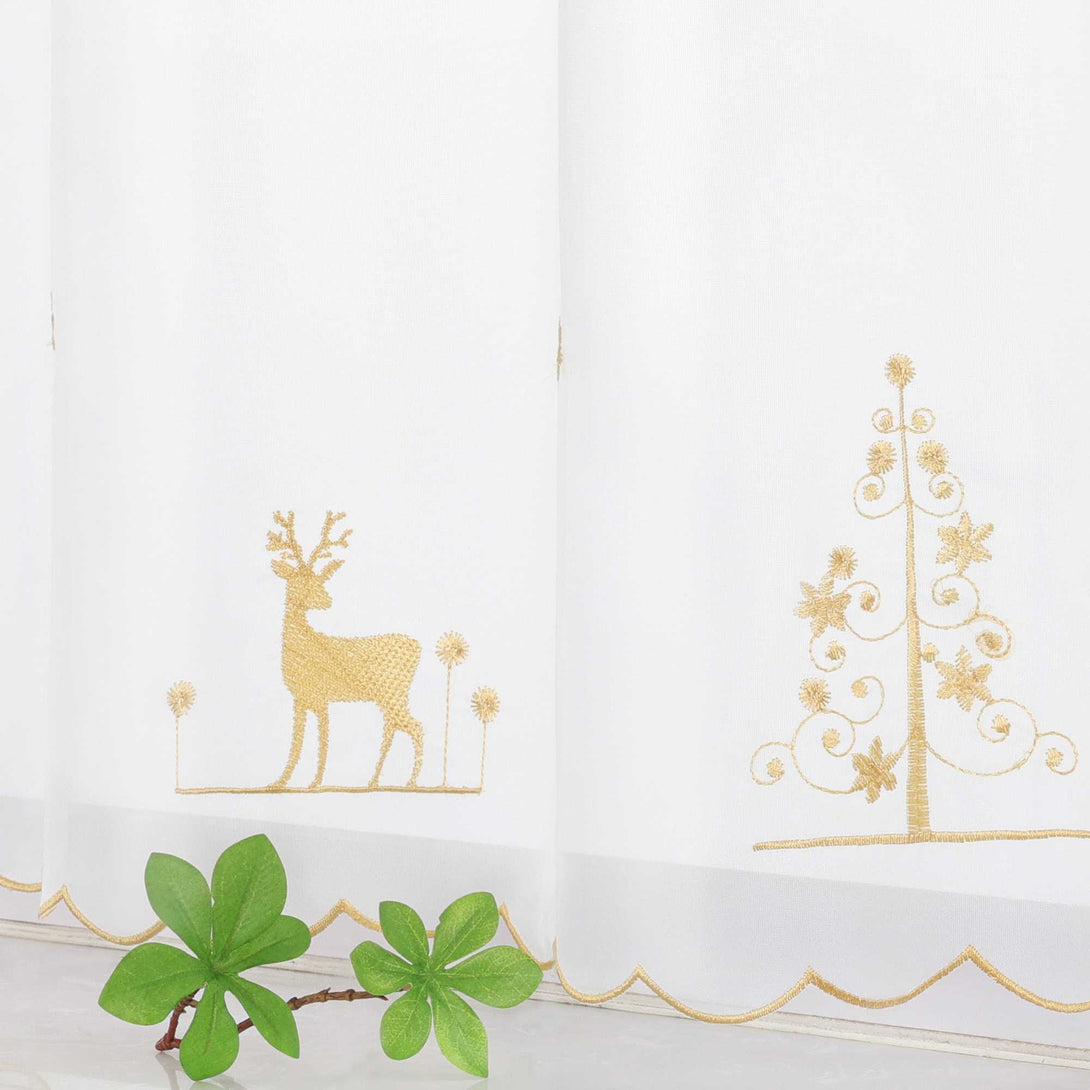 Die transparente Kurzgardine hängt elegant vor einem weißen Fenster. Sie ist mit goldenen Nähten verziert, die das Design perfekt abrunden. Die handgestickten Motive von goldenen Rentieren und einem goldenen Weihnachtsbaum sind äußerst detailliert und präzise verarbeitet. Jedes Stichmuster ist gleichmäßig und fein, was die hochwertige Handarbeit widerspiegelt. Die Schneeflocken ergänzen das Design und verleihen der Gardine einen festlichen Touch.