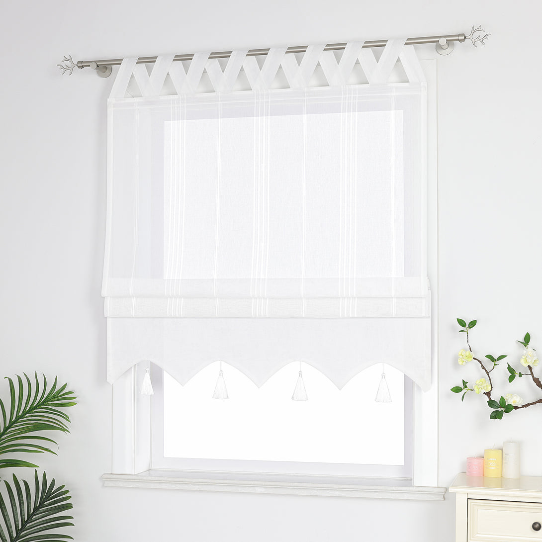 Seitenansicht eines weißen Raffrollos mit Quasten und Schlaufen – halb geschlossen, sodass die Fenster nicht vollständig bedeckt sind, neben Grünpflanzen und duftenden Ornamenten.