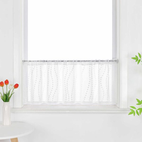 Die weiße, transparente Scheibengardine hängt vor einem Fenster und zeigt ein elegantes 3D-Punktemuster auf der Oberfläche. Der Fensterbereich wird durch grüne Pflanzen dekoriert, die dem Raum eine frische und lebendige Atmosphäre verleihen.