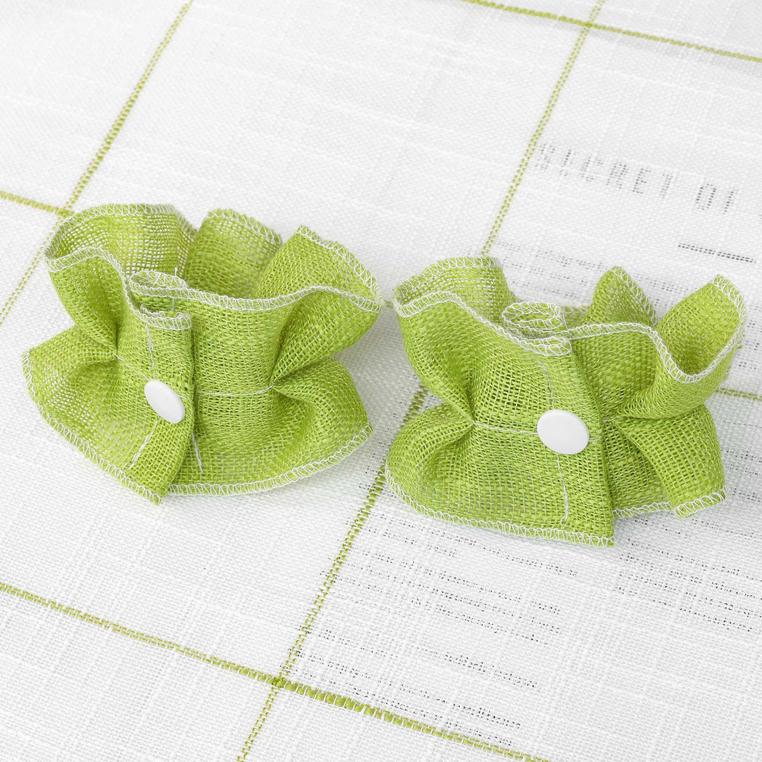 Zwei grüne, elegantly gefältelte Dekorationskomponenten aus feinstem Polyester, jedes mit einer zierlichen weißen runden Dekoration in der Mitte.
