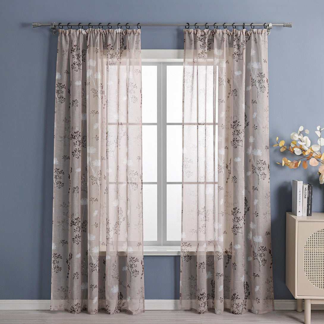 Das Bild zeigt ein Fenster, an dem hellbraune Voile-Vorhänge mit Blumenmuster hängen. Neben dem Fenster befindet sich eine blaue Wand, und in der Ecke steht ein heller Schrank, auf dem Bücher und ein dekorativer Blumenstrauß arrangiert sind. Diese Kombination schafft eine warme und natürliche Wohnatmosphäre.
