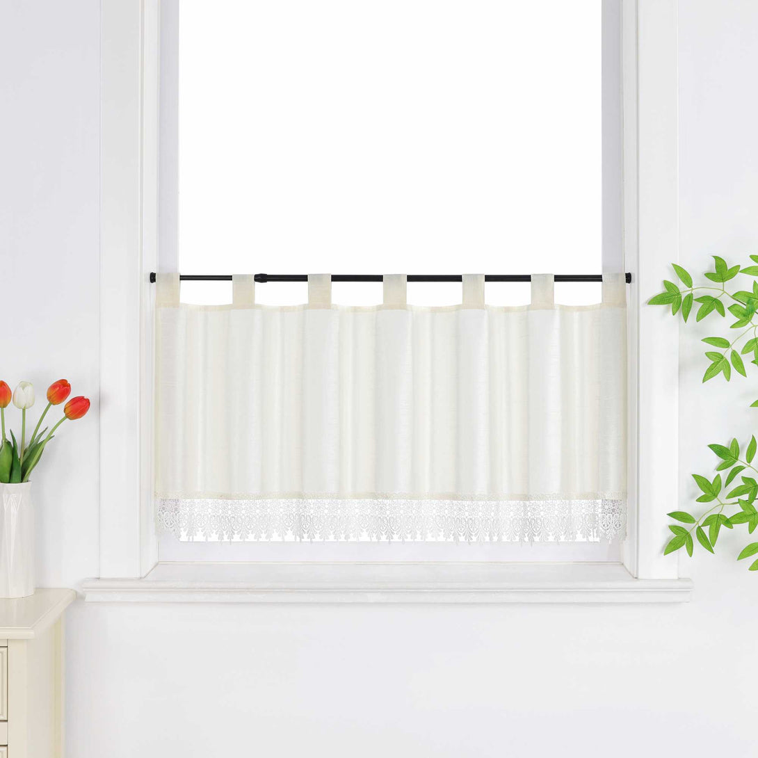Beige Scheibengardine hängt vor einem Fenster mit weißer Wand. Daneben sorgen rote Blumen, grüne Blätter und eine Vase für eine frische und dekorative Note.
