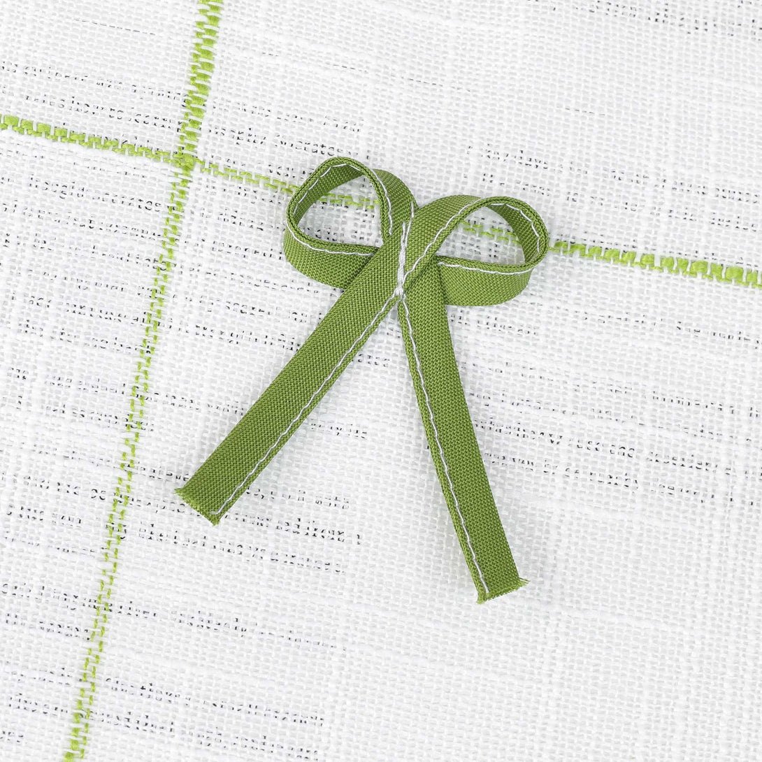 Dies ist eine grüne Schleifendekoration, die an einem weißen Gewebe mit hellgrünen Linien befestigt ist. Die Schleife ist aus geripptem Bandzeug hergestellt, mit ordentlichen Nahten und gleichmäßiger Farbgebung. Sie verleiht dem Gewebe Raffinesse und Dekorierbarkeit und wird häufig zur Verschönerung von Gardinen, Kleidungsstücken und anderen Gegenständen eingesetzt, um einen frischen und süßen Stil zu kreieren. 