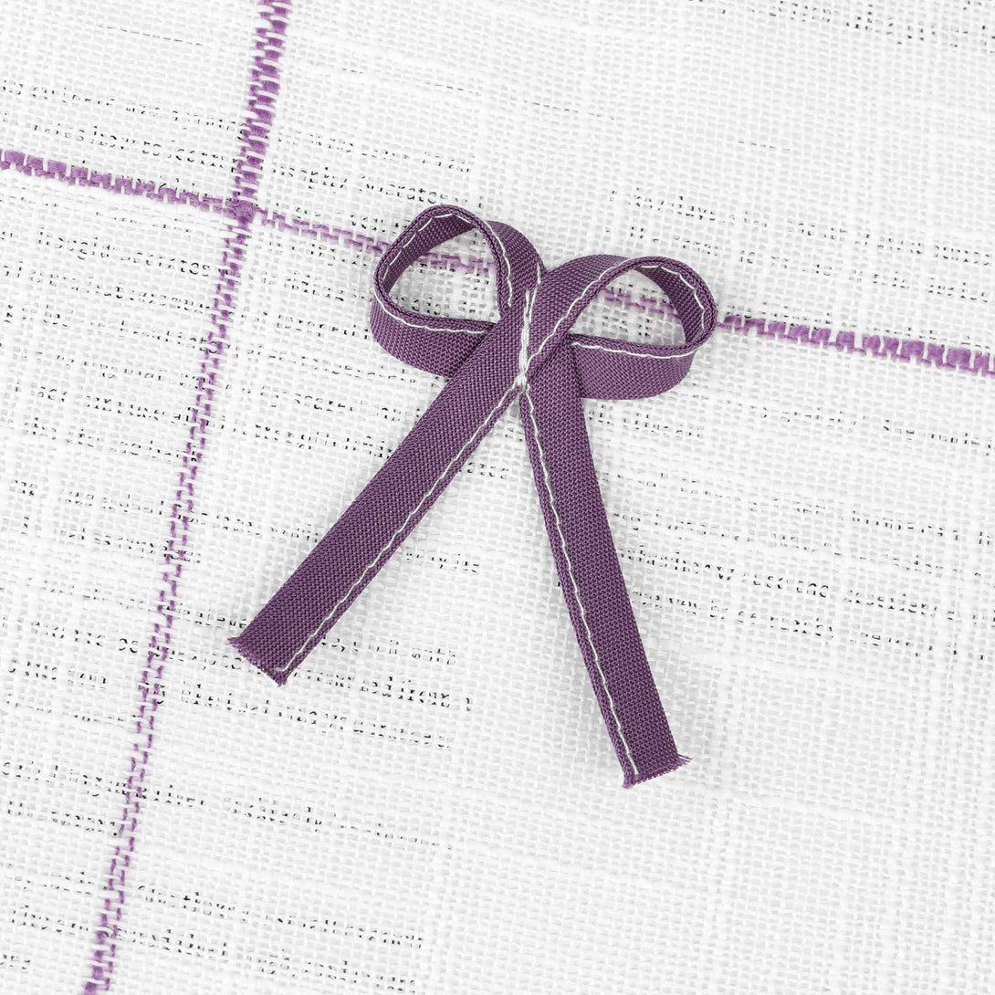Dies ist eine violette Schleife, die an einem weißen Gewebe mit violetten Linien befestigt ist.