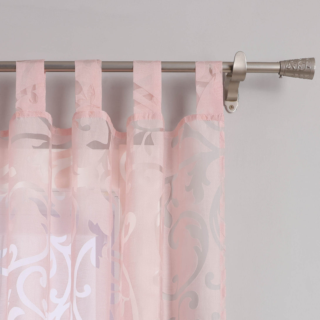Dies ist eine Nahaufnahme des Aufhängesystems eines rosa, durchsichtigen Vorhangs mit Blumenmuster. Der Vorhang wird mit rosa Stoffringen an einer Metallstange befestigt, deren ein Ende mit dekorativen Elementen verziert ist.