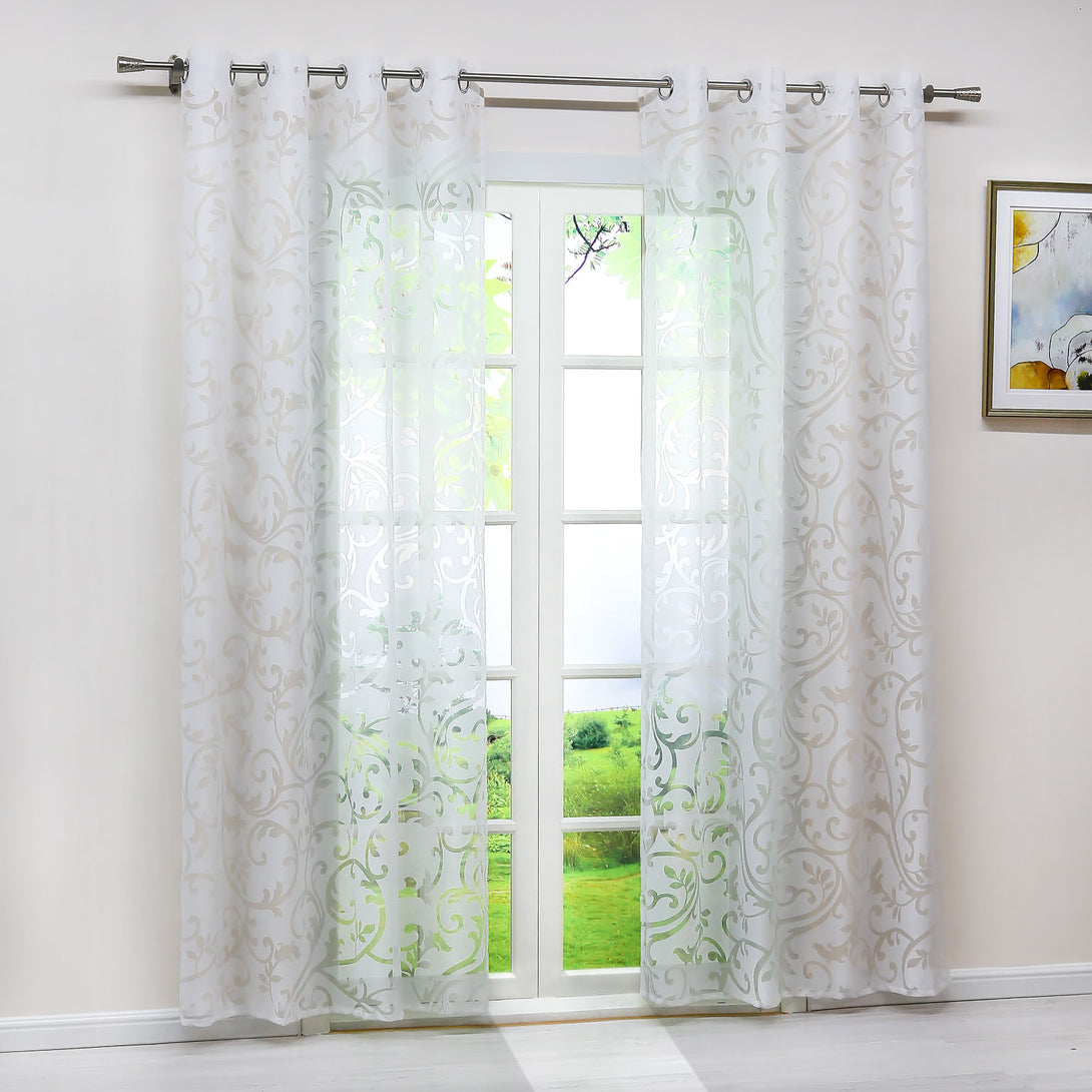 Dies ist ein Bild eines Fensters, an dem ein weißer, durchsichtiger Vorhang mit Blumenmuster hängt. Durch den Vorhang ist die grüne Landschaft draußen sichtbar. Der Vorhang wird durch Metallringe an einer Metallstange aufgehängt. An der Wand neben dem Fenster hängt ein dekoratives Bild.